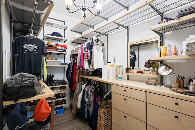 spacious closet with a notable chandelier and dark wood-type flooring