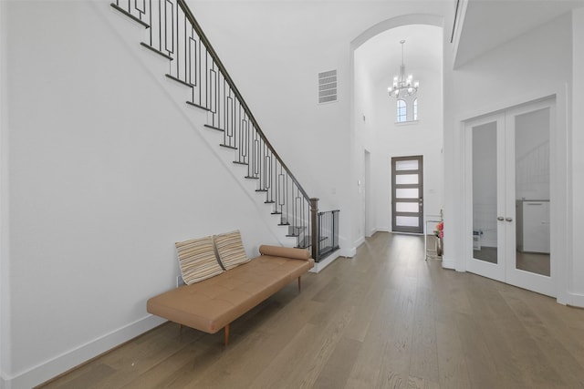 foyer featuring a chandelier, french doors, a high ceiling, and wood-type flooring