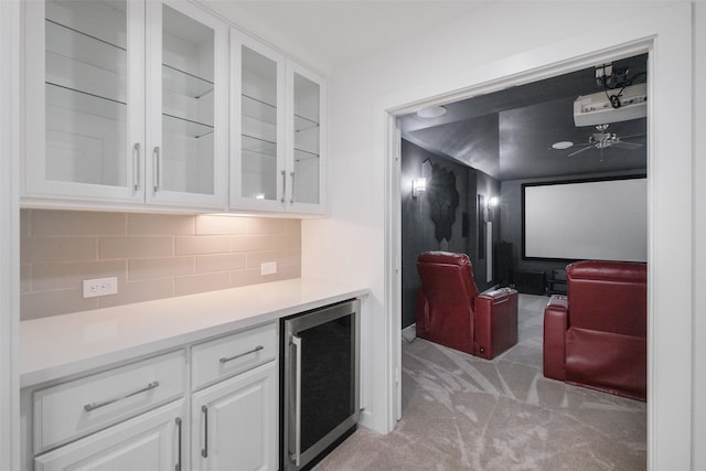 kitchen with decorative backsplash, wine cooler, light colored carpet, and white cabinetry