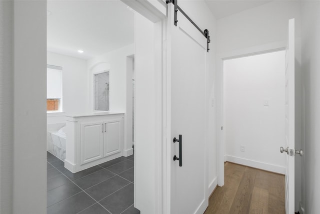 hallway featuring a barn door and dark tile patterned flooring