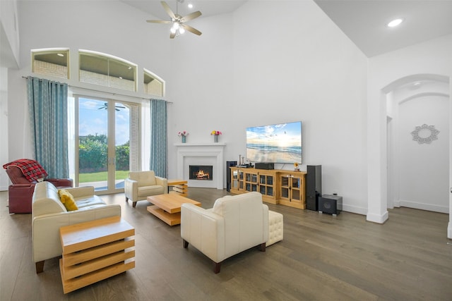 living room featuring ceiling fan, dark hardwood / wood-style floors, and a high ceiling