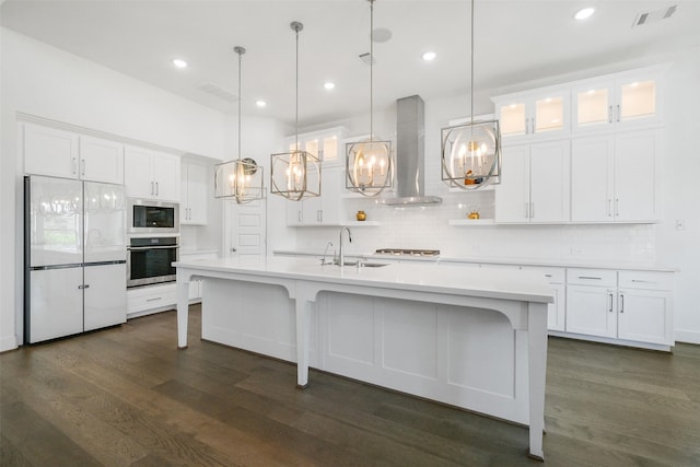 kitchen with built in appliances, white cabinetry, and wall chimney exhaust hood