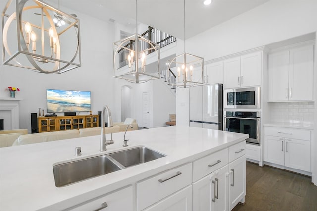 kitchen featuring tasteful backsplash, stainless steel appliances, sink, white cabinetry, and hanging light fixtures