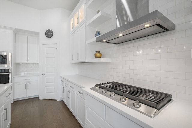 kitchen with dark hardwood / wood-style flooring, tasteful backsplash, stainless steel appliances, wall chimney range hood, and white cabinetry