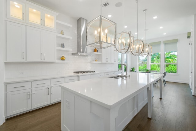 kitchen featuring island exhaust hood, white cabinetry, sink, and a kitchen island with sink