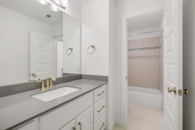 bathroom with tile patterned flooring, vanity, and tiled shower / bath