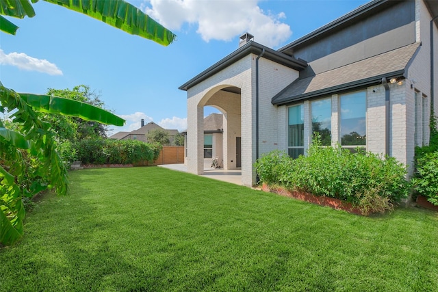 back of house with a patio and a lawn