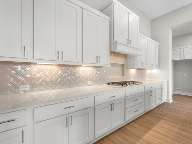 kitchen with light stone countertops, white cabinets, and stainless steel gas stovetop