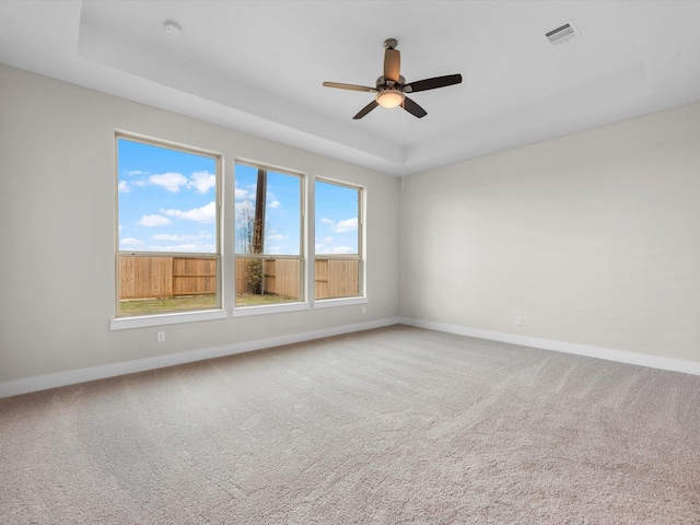 empty room with carpet, a raised ceiling, and ceiling fan