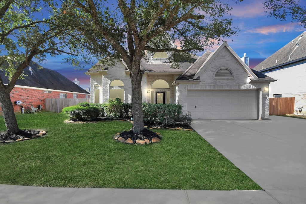 view of front of home with a garage and a lawn