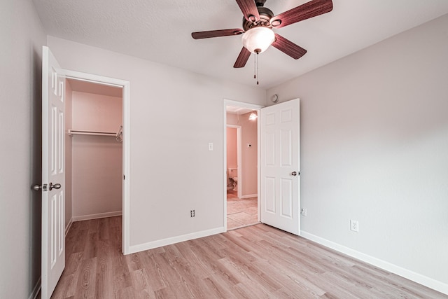 unfurnished bedroom featuring ceiling fan, light hardwood / wood-style floors, a spacious closet, and a closet