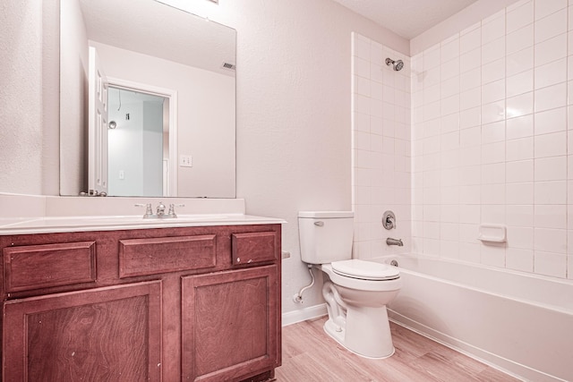 full bathroom featuring hardwood / wood-style flooring, tiled shower / bath combo, toilet, and vanity