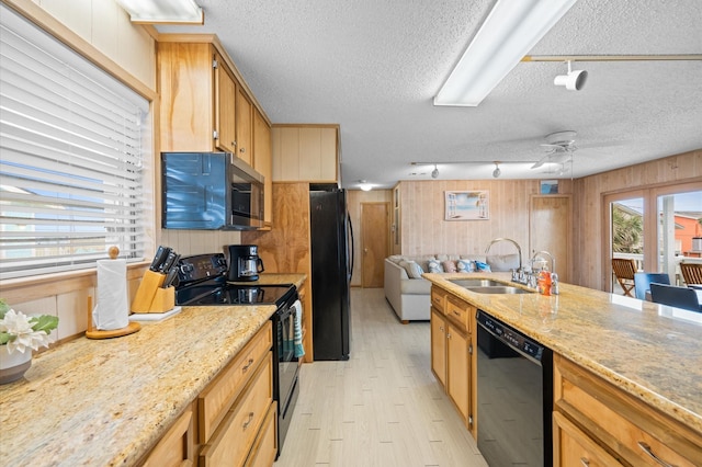 4406 Pabst Rd, Galveston, TX 77554 - kitchen featuring a textured ceiling, light wood-style flooring, a sink, wood walls, and black appliances