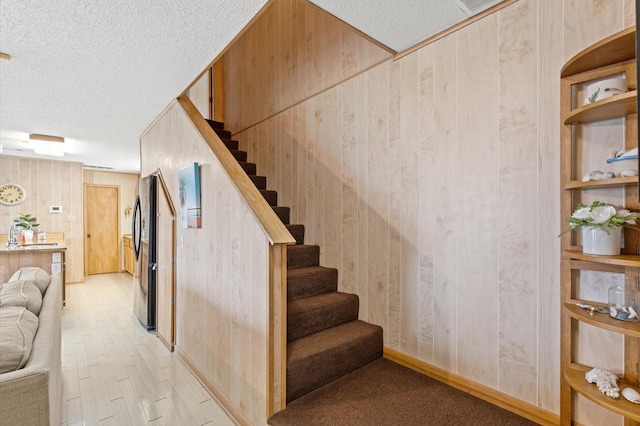 stairway with wooden walls and hardwood / wood-style flooring