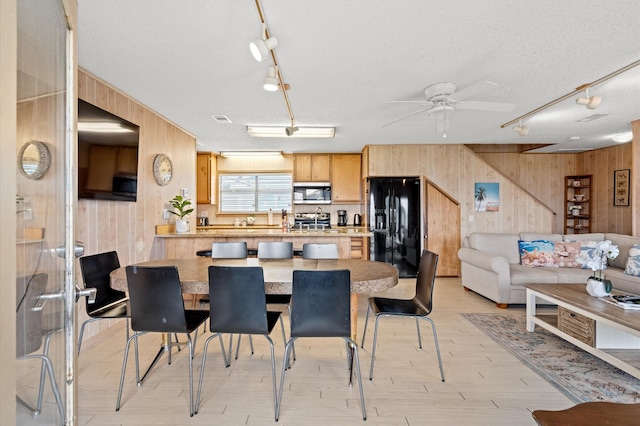 interior space with wooden walls, ceiling fan, a textured ceiling, and appliances with stainless steel finishes