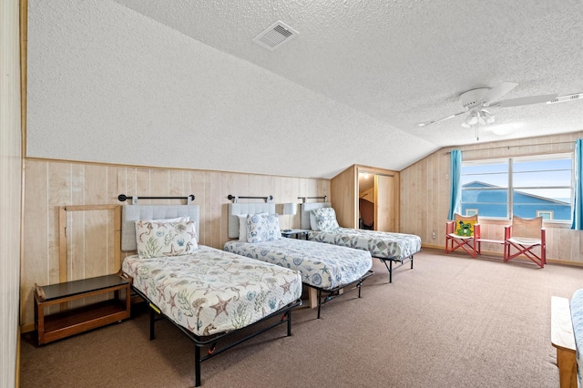 carpeted bedroom with a textured ceiling, ceiling fan, and lofted ceiling