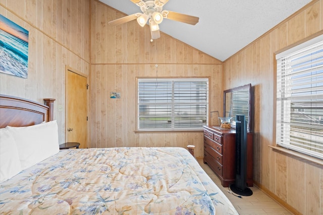 bedroom with multiple windows, wooden walls, ceiling fan, and lofted ceiling