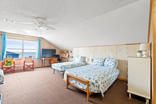 bedroom with a textured ceiling, carpet floors, vaulted ceiling, and ceiling fan