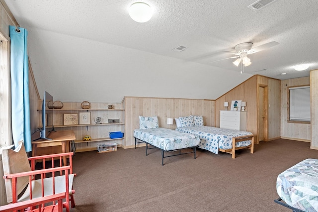 carpeted bedroom featuring a textured ceiling, vaulted ceiling, ceiling fan, and wood walls