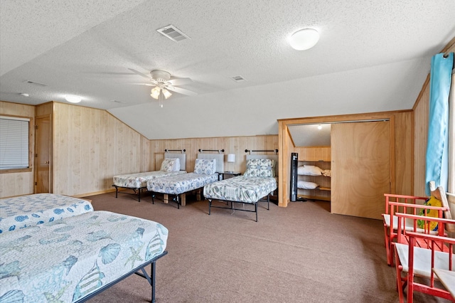 carpeted bedroom featuring a textured ceiling, ceiling fan, lofted ceiling, and wood walls