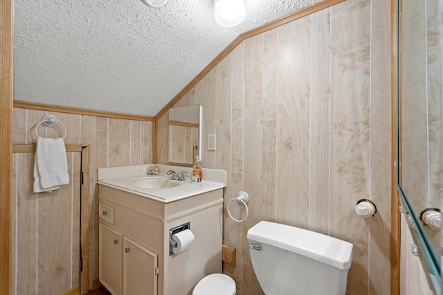 bathroom with ornamental molding, vanity, toilet, lofted ceiling, and wood walls