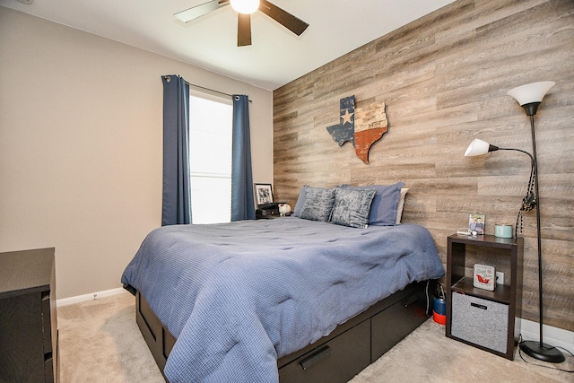 carpeted bedroom featuring wood walls and ceiling fan