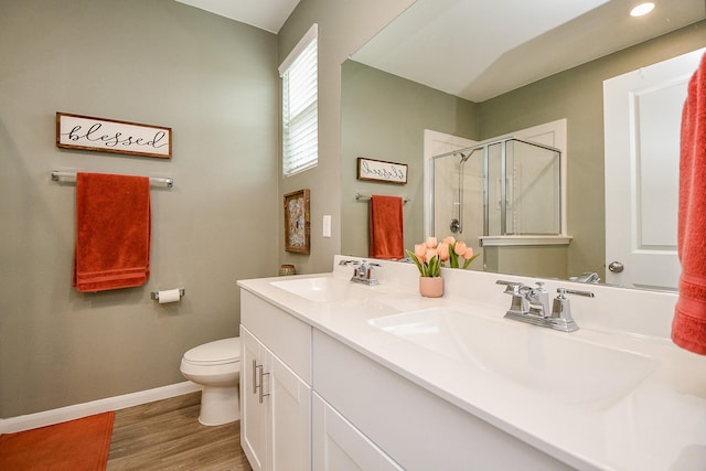 bathroom with wood-type flooring, vanity, toilet, and a shower with door