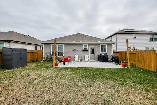 back of house with a yard, a patio, and a storage shed