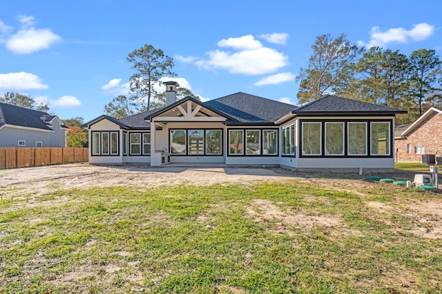 rear view of house featuring a sunroom, cooling unit, and a lawn