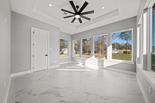 unfurnished sunroom featuring a raised ceiling and ceiling fan