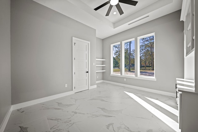 unfurnished room featuring ceiling fan and a raised ceiling