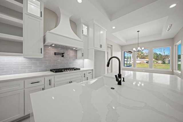 kitchen featuring white cabinetry, stainless steel gas stovetop, sink, and custom exhaust hood