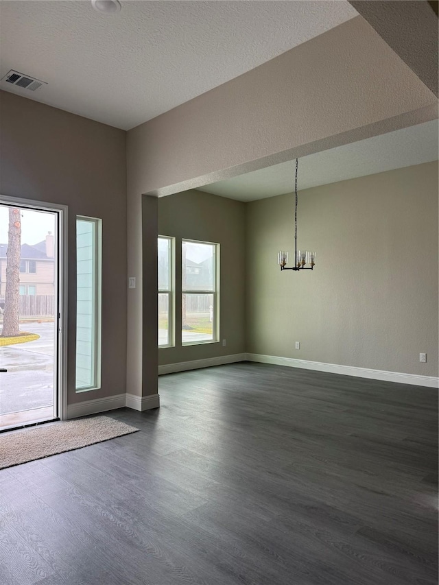 interior space with a textured ceiling, dark wood-type flooring, and an inviting chandelier