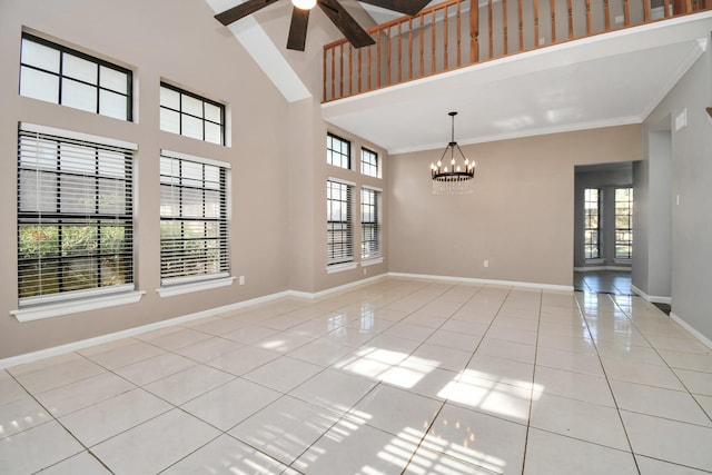 tiled spare room featuring a towering ceiling and ceiling fan with notable chandelier