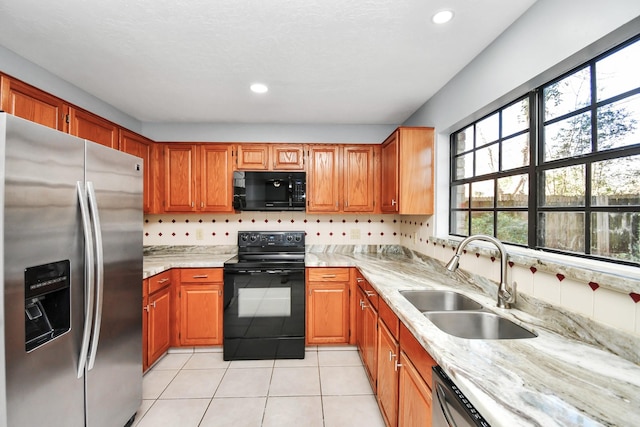 kitchen featuring black appliances, light stone countertops, light tile patterned floors, and sink