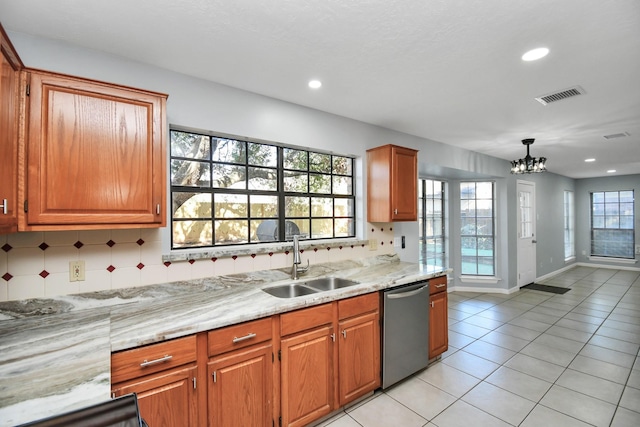 kitchen featuring stainless steel dishwasher, hanging light fixtures, sink, tasteful backsplash, and an inviting chandelier