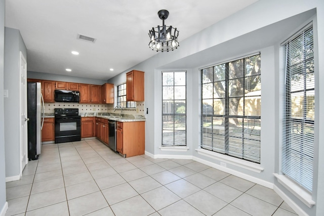 kitchen featuring hanging light fixtures, sink, light stone counters, black appliances, and an inviting chandelier