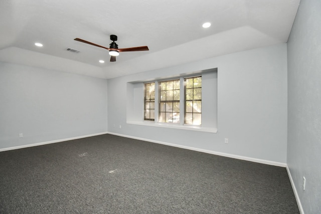 empty room with ceiling fan, lofted ceiling, and dark colored carpet