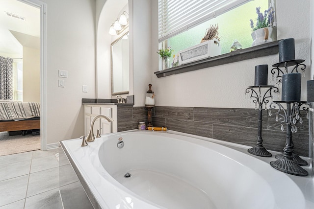 bathroom with tiled tub, vanity, plenty of natural light, and tile patterned floors