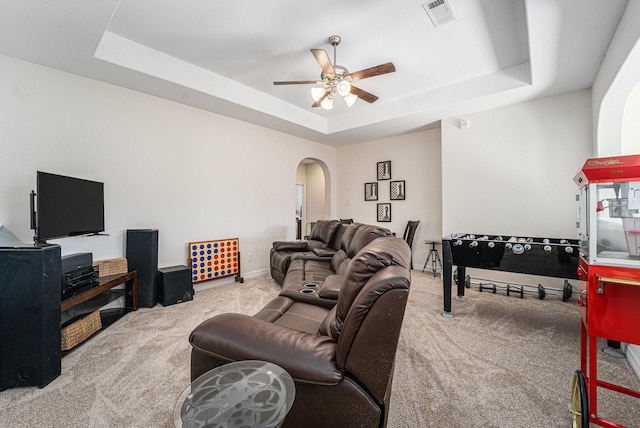 living room with a tray ceiling, ceiling fan, and carpet flooring