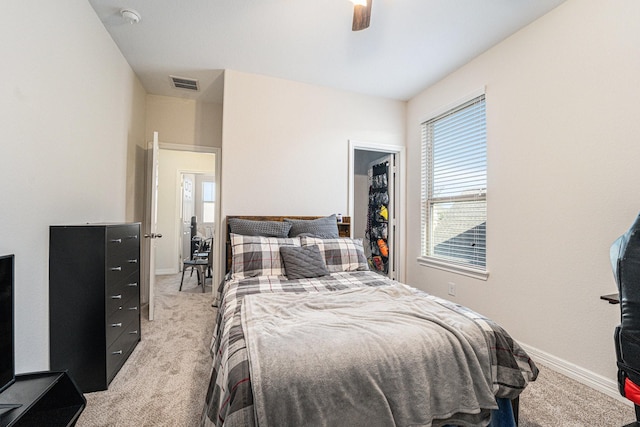 carpeted bedroom featuring a walk in closet and ceiling fan