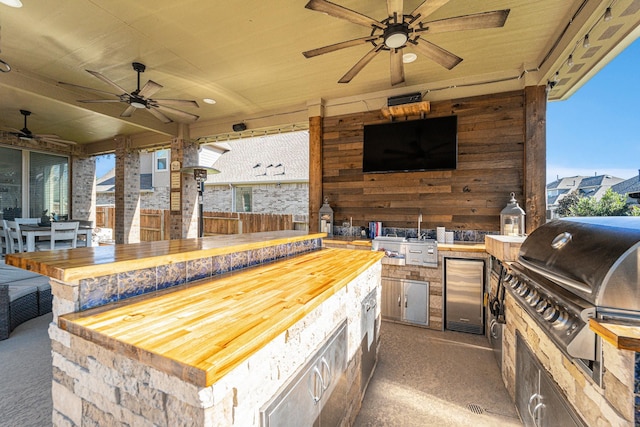 view of patio / terrace with a bar, area for grilling, ceiling fan, and exterior kitchen