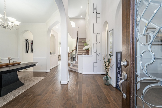 foyer featuring dark hardwood / wood-style flooring, crown molding, and an inviting chandelier