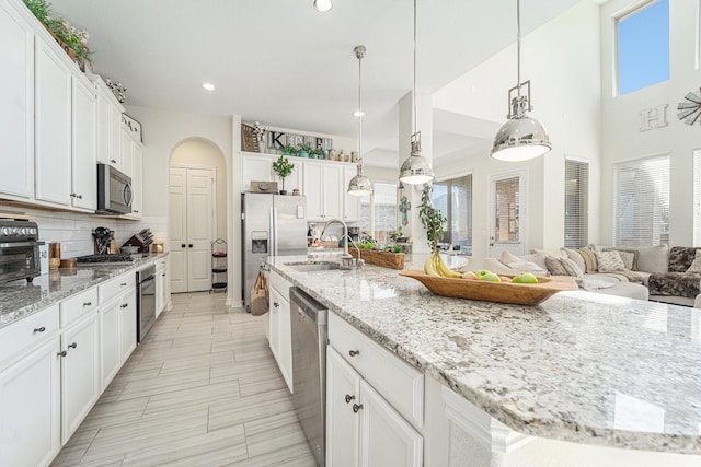 kitchen featuring appliances with stainless steel finishes, light stone countertops, hanging light fixtures, and white cabinets