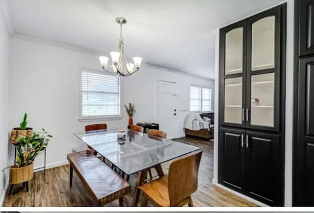 dining room with hardwood / wood-style floors, an inviting chandelier, and ornamental molding