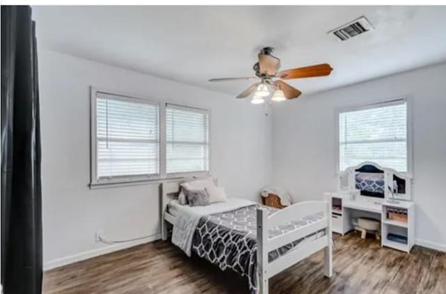 bedroom featuring ceiling fan, dark wood-type flooring, and multiple windows