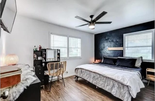 bedroom with multiple windows, hardwood / wood-style flooring, and ceiling fan