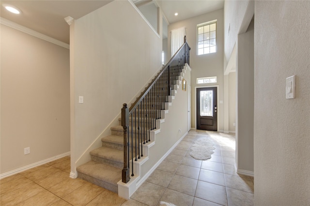 tiled foyer entrance featuring crown molding and a towering ceiling