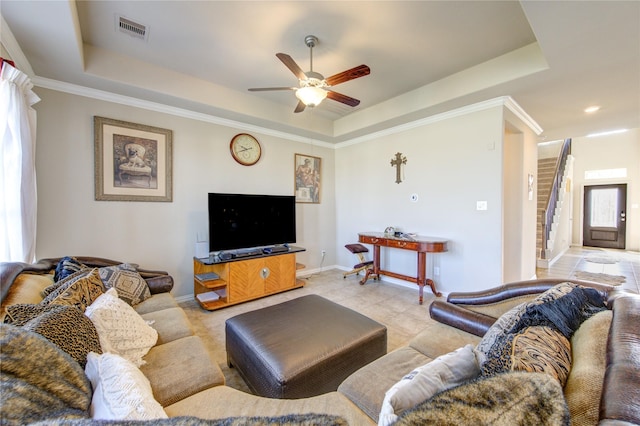 living room with a tray ceiling, ceiling fan, and ornamental molding