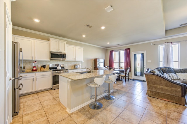 kitchen featuring white cabinets, stainless steel appliances, a center island with sink, and sink